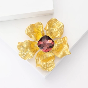 Exquisite goldene Blumenbrosche mit matter Textur und lila Edelsteinzentrum in 45-Grad-Ansicht