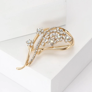 Elegante spilla a fiore dorata con strass di cristallo su supporto geometrico bianco