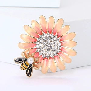 Vista macro della spilla girasole con petali in smalto rosa, ape e strass brillanti