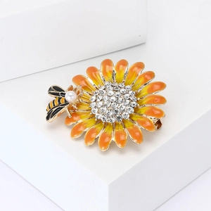 Spilla con girasole e ape in smalto con strass su un espositore bianco moderno