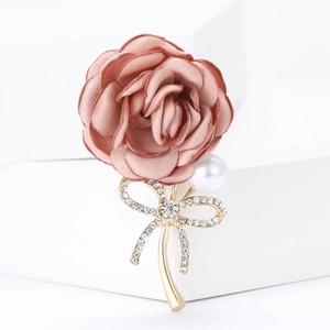 Detail of fabric rose brooch with white pearl and rhinestone studded golden bow