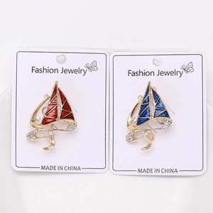 Detail of gold sailboats brooches with red and blue enamel and sparkling rhinestones