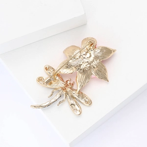 Detailed back view of a golden lotus and dragonfly brooch showing the safety pin fastener