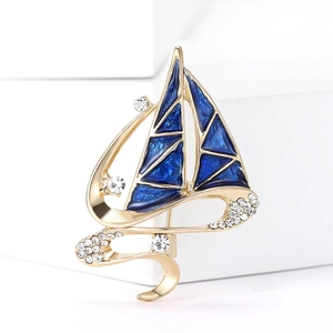 Macro detail of yacht brooch with blue enamel sails and sparkling crystal inlay