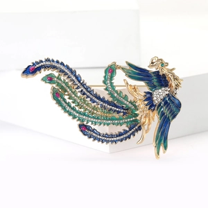 Détail d'une élégante broche phénix dorée avec ailes en émail et cristaux brillants