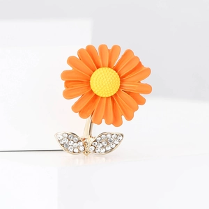 Détail de la broche marguerite en émail orange avec feuilles ornées de strass brillants