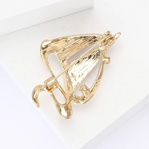 Detailed back view of gold sailing brooch showing pin clasp and textured metal finish