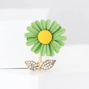 Détail de la broche marguerite en émail avec pétales verts et strass brillants