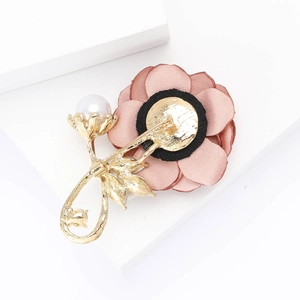 Détail de la broche fleur en tissu rose avec feuilles dorées et perle blanche