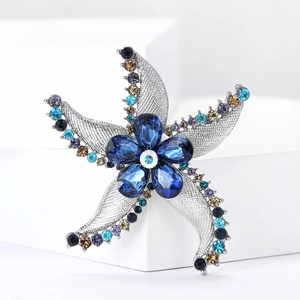 Sparkling crystal starfish brooch pin with blue floral center on white display stand