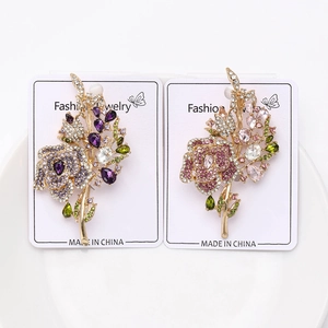 Dettaglio di spille bouquet di rose con cristalli viola e rosa su base in metallo dorato