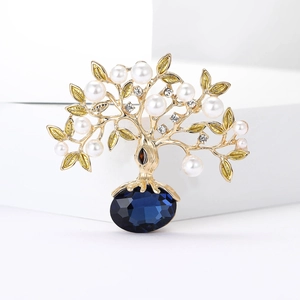 Gros plan détaillé de la broche arbre de vie avec branches dorées, perles et gemme bleue