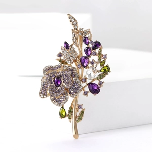 Dettaglio macro di spilla floreale di lusso con cristalli viola e verdi su lega dorata