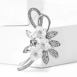 Nahaufnahme der eleganten Pflaumenblüten-Brosche mit weißen Emaille-Blüten und Strasssteinen