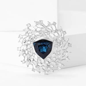 Macro view of a luxury brooch with a deep blue triangle cut stone and micro-pave crystals