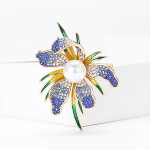 Close-up of orchid brooch with blue rhinestones, white pearl and colorful enamel details