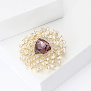 Radial flower brooch with large purple gem and clear zircons on gold metal base