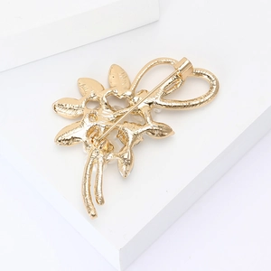 Detailansicht der Rückseite der goldenen Blumenbrosche mit Anstecknadel und Textur