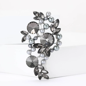 Close-up of vintage floral brooch with dark grey crystals and pearls on silver base