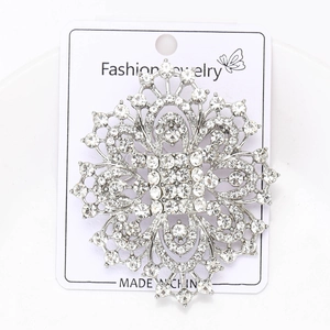 Detailed macro view of a silver snowflake brooch with sparkling rhinestones on paper card