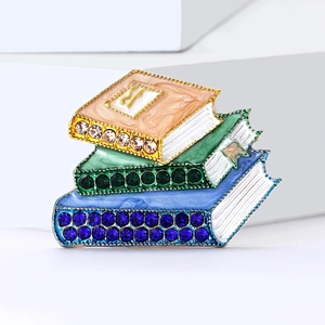 Broche créative en émail avec trois livres empilés, strass colorés et bordures dorées