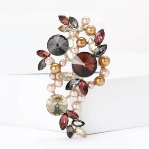 Vintage alloy brooch with pearls and colorful crystals on a white geometric stand