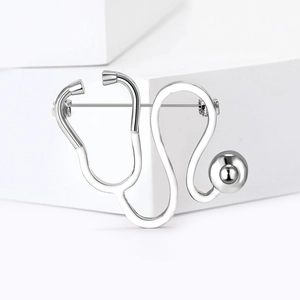 Gros plan d'une broche stéthoscope argentée montrant la texture du métal et l'épingle au dos