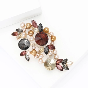 Vintage floral brooch with crystal rhinestones and pearls on a sleek white pedestal