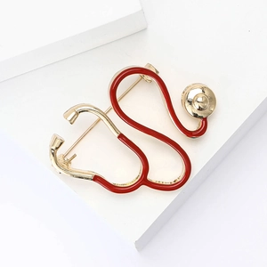 Vue macro d'une broche stéthoscope créative en émail rouge et or avec épingle