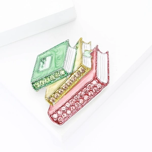 Détail de la broche en forme de livres empilés avec émail coloré et strass brillants