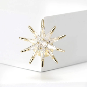 Elegant gold eight-point star brooch with micro-paved cubic zirconia on white pedestal