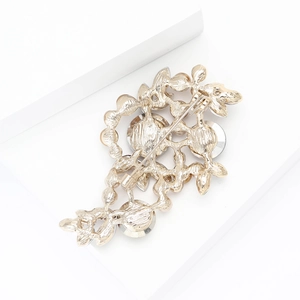 Detailed back view of a gold floral brooch with crystals and a secure metal pin fastener