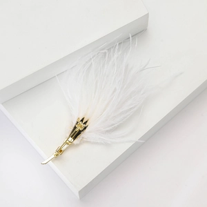 Détail d'une broche en plumes blanches duveteuses avec une base en métal doré élégante