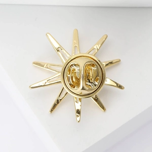 Detailed back view of gold starburst brooch showing the metal butterfly clutch fastener