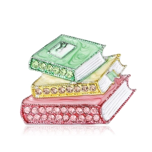 Stack of three colorful enamel books brooch pin with rhinestones on a white background