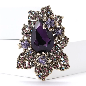 Détail macro d'une broche fleurie vintage avec pierre violette en poire et petits cristaux
