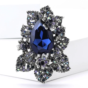 Détail d'une broche vintage avec pierre bleue en goutte d'eau et strass violets