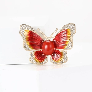 Détail macro d'une broche papillon haut de gamme en émail rouge et cristaux dorés