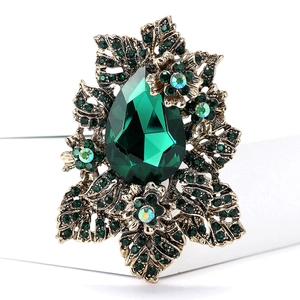 Vue macro d'une broche vintage ornée d'une pierre vert émeraude et de motifs floraux