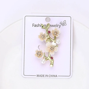 Detailaufnahme einer goldenen Zweig-Brosche mit Emaille-Blumen und funkelnden Kristallen