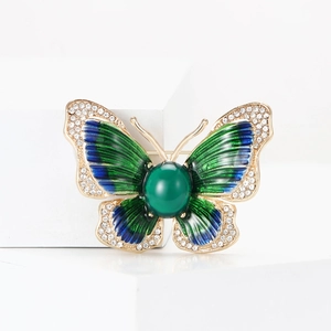 Détail de la broche papillon dorée avec émail vert et strass étincelants