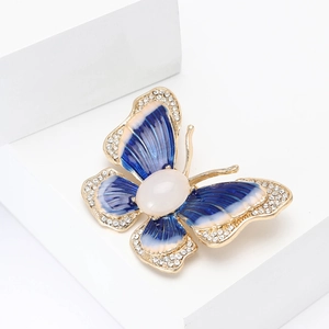 Élégante broche papillon en émail bleu et cristaux sur un piédestal blanc épuré