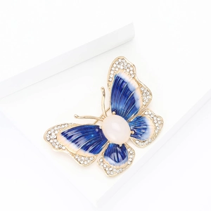 Détails macro d'une broche papillon en émail avec cadre doré et cristaux blancs