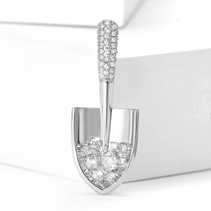 Close-up of shovel-shaped brooch featuring pavé zircon stones and polished silver finish