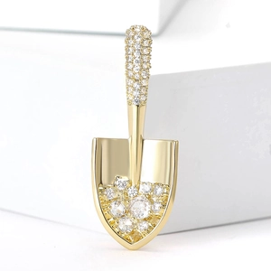 Elegant gold shovel brooch with cubic zirconia crystals on a modern white background