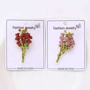 Dettaglio delle spille a bouquet di rose in smalto rosso e rosa su scheda espositiva