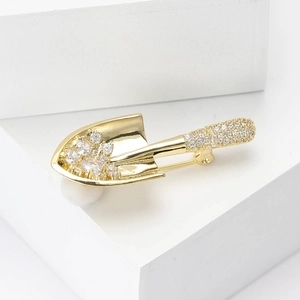 Creative copper zircon shovel brooch with gold plating and sparkling crystals on white base