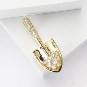 Creative gold-plated shovel brooch with shimmering cubic zirconia on white steps
