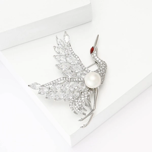 Elegant crane brooch with sparkling cubic zirconia and a white pearl on a silver-tone base