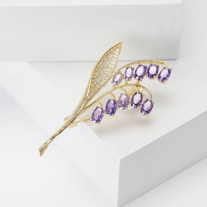 Elegante spilla a mughetto con gemme viola e zirconi bianchi su base dorata lucida